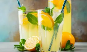 Orzeźwiająca lemoniada z limonki z plasterkami cytryny i listkami mięty w szklankach i dzbanku.