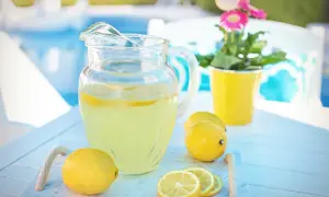 Orzeźwiająca lemoniada z kiszonych cytryn w dzbanku, obok świeże cytryny i plasterki. Idealna na upalne dni.