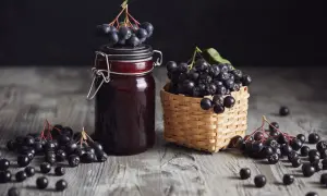 Słoik z nalewką z aronii i koszyczek pełen owoców. To przepis babci na zdrowie!