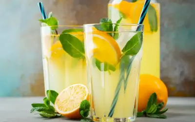 Orzeźwiająca lemoniada z limonki z plasterkami cytryny i listkami mięty w szklankach i dzbanku.